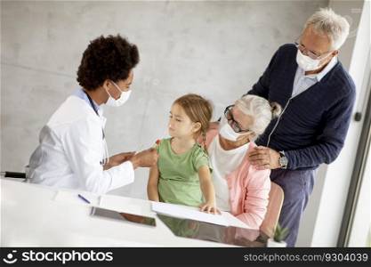 Senior couple with cute grandaughter black female doctor in the office