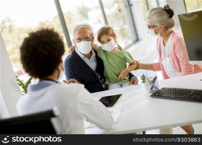 Senior couple with cute granddaughter black female doctor in the office