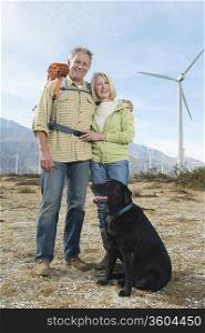 Senior couple with dog near wind farm