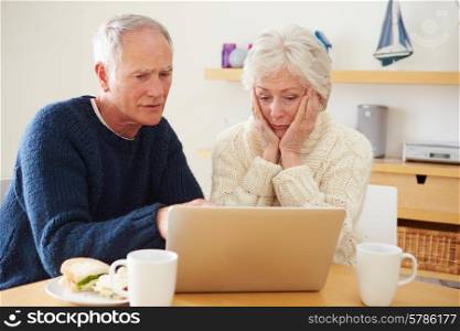 Senior Couple With Financial Problems Looking At Laptop