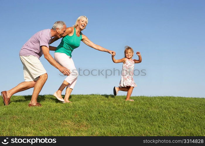 Senior couple, with granddaughter, running though field