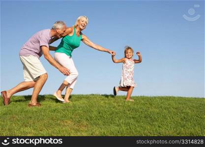 Senior couple, with granddaughter, running though field