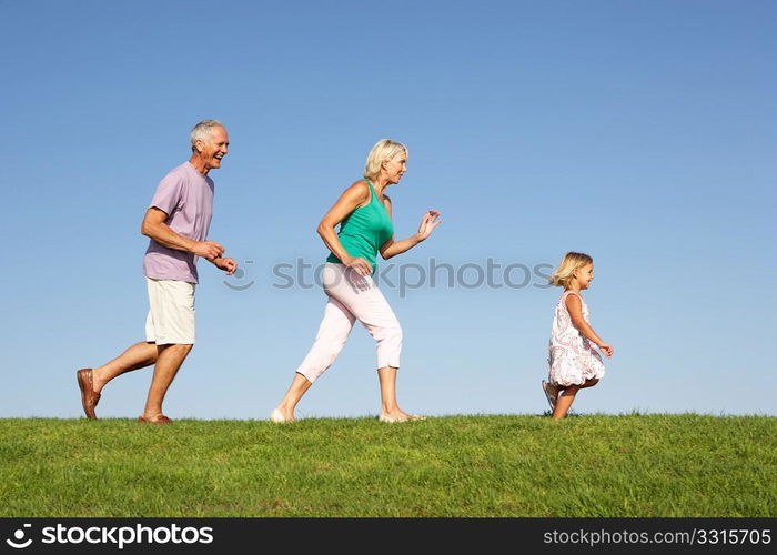 Senior couple, with granddaughter, running though field