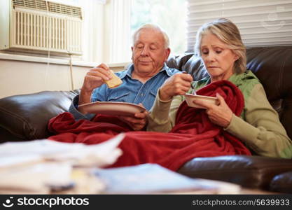 Senior Couple With Poor Diet Keeping Warm Under Blanket