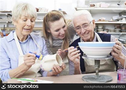 Senior Couple With Teacher In Pottery Class