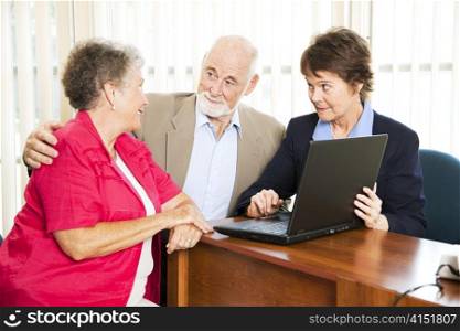 Senior couple with their financial advisor, going over their retirement income on her computer.