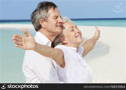 Senior Couple Withs Arms Outstretched On Beautiful Beach