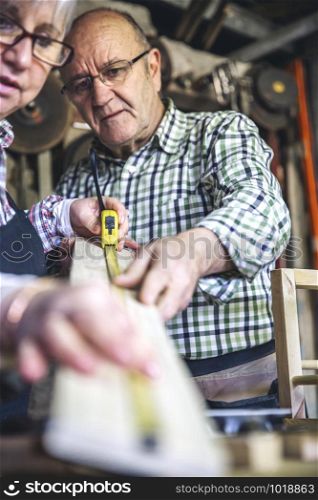 Senior couple working in a carpentry workshop. Selective focus on man in background. Senior couple in a carpentry