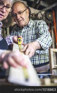 Senior couple working in a carpentry workshop. Selective focus on man in background. Senior couple in a carpentry