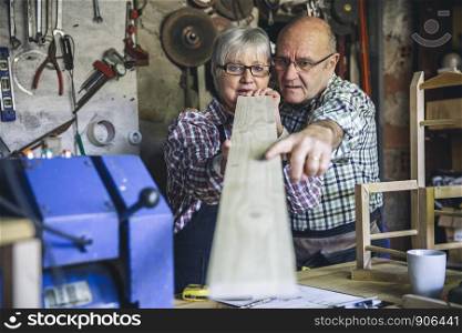 Senior couple working in a carpentry workshop. Selective focus on people in background. Senior couple in a carpentry