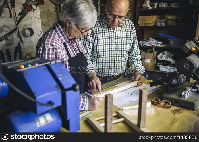 Senior couple working in a carpentry workshop. Senior couple in a carpentry