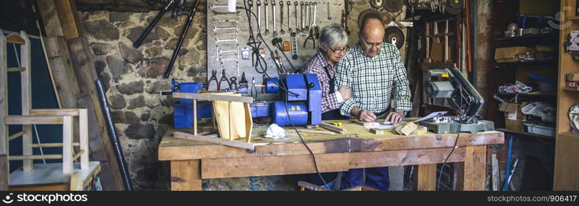 Senior couple working in a carpentry workshop. Senior couple in a carpentry