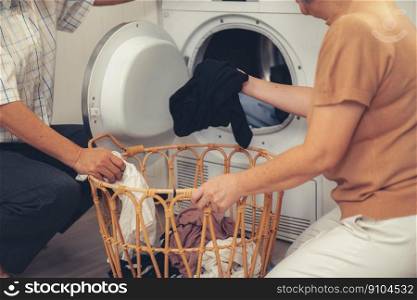 Senior couple working together to complete their household chores at the washing machine in a happy and contented manner. Husband and wife doing the usual tasks in the house.. Contented senior couple doing laundry together.