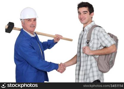 senior craftsman and apprentice shaking hands