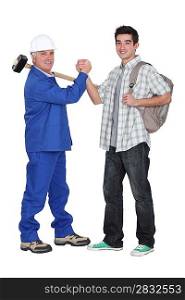 senior craftsman and young apprentice shaking hands