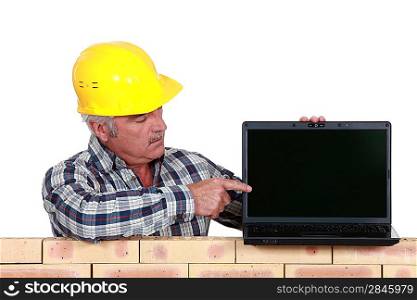 senior craftsman pointing at his laptop
