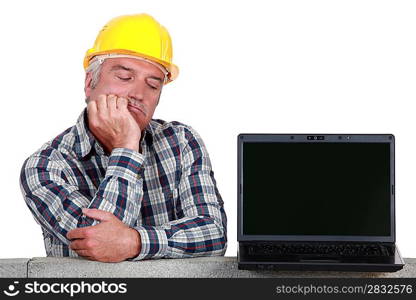 senior craftsman posing next to a laptop