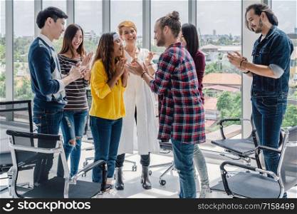 Senior creative manager man giving the new about promote the position to the asian junior working woman in center of Group Of Asian and Multiethnic Business people encourage together, diverse concept