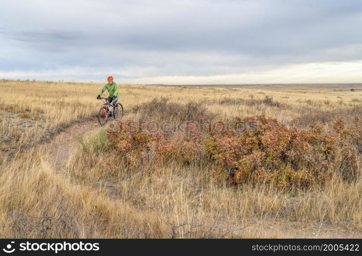 senior cyclist is riding mountain bike on a single track trail in Colorado prairie - Soapstone Prairie Natural Area with last fall colors in late October
