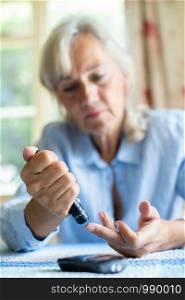 Senior Diabetic Woman Testing Blood Sugar Level At Home