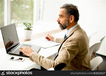 Senior  director sitting at desk and working on laptops in the office