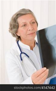 Senior doctor female hold and looking at x-ray with stethoscope