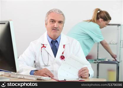 senior doctor in his surgery with nurse in background