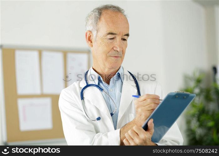 senior doctor man filling up medical form at clipboard