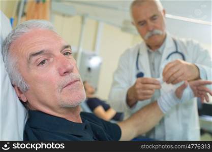 senior doctor putting a bandage on an elder mans arm