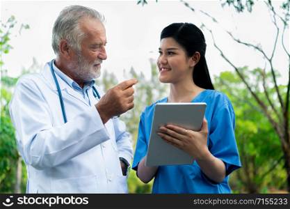 Senior doctor with young doctor in the park. Medical healthcare staff and doctor service.