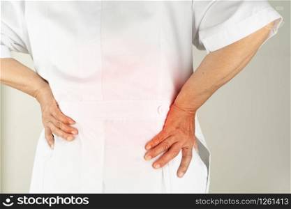senior doctor woman suffering of backache, touching back with hand, muscular pain over white background