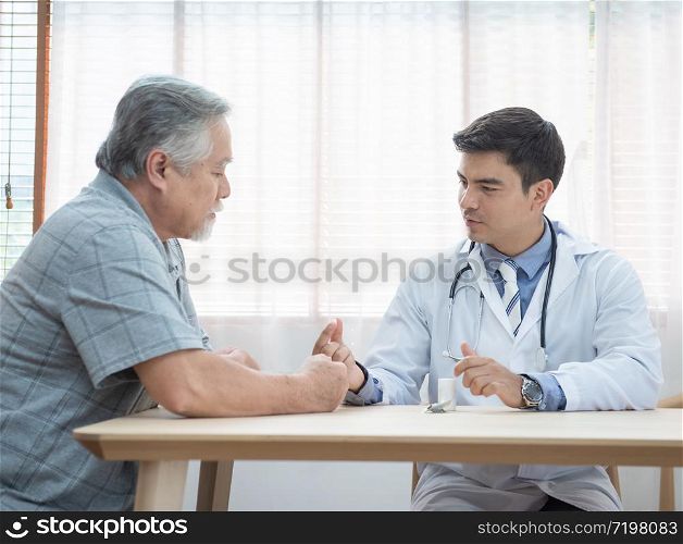 Senior elder asian man asking young caucasian doctor about indications and contraindications of new medicine, healthcare and medicine concept with copy space.