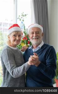 senior elderly caucasian old man and woman dancing together in living room that decorated with christmas tree for christmas festival day, retirement lifestyle concept