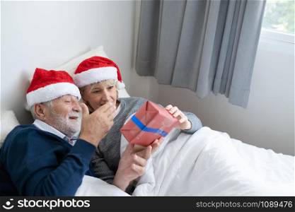 senior elderly caucasian old man give gift presents to woman, they happy together in bedroom for christmas festival day in the morning, retirement lovely couple lifestyle concept