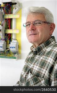 Senior electrician standing by fusebox