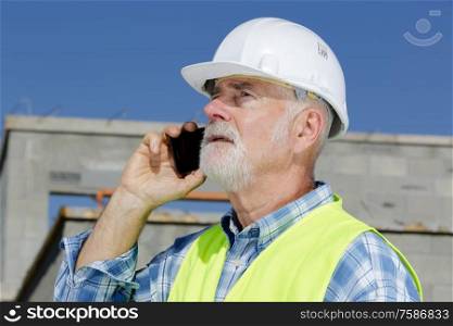 senior engineer man in suit and helmet talking mobile phone