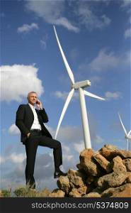 senior engineer phoning outdoors near windmills