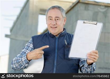 senior engineer standing holding a clipboard and pointing