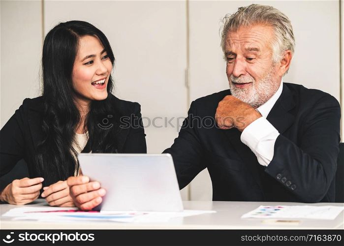 Senior executive manager and young businesswoman working in meeting room in the office. The woman is secretary or translator. International business language translation concept.