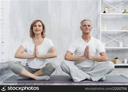 senior family couple sitting lotus pose grey yoga mat