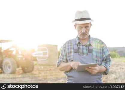 Senior farmer using digital tablet while standing at farm