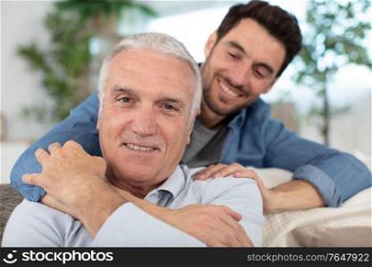 senior father and smiling young adult grown son relaxing together