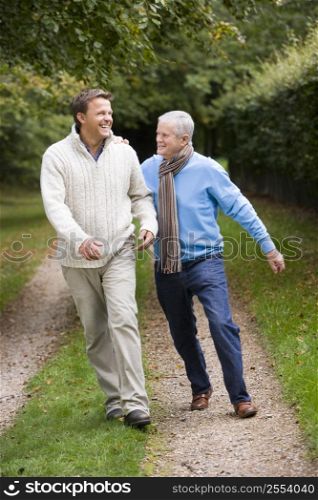 Senior father and son walking on path outdoors smiling
