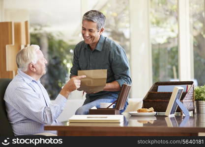 Senior Father Discussing Document With Adult Son
