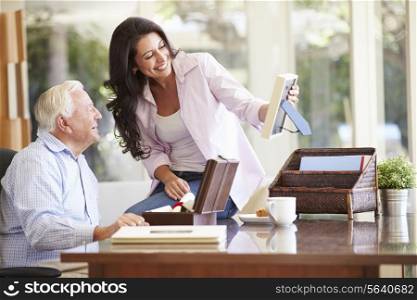 Senior Father Looking At Photo In Frame With Adult Daughter