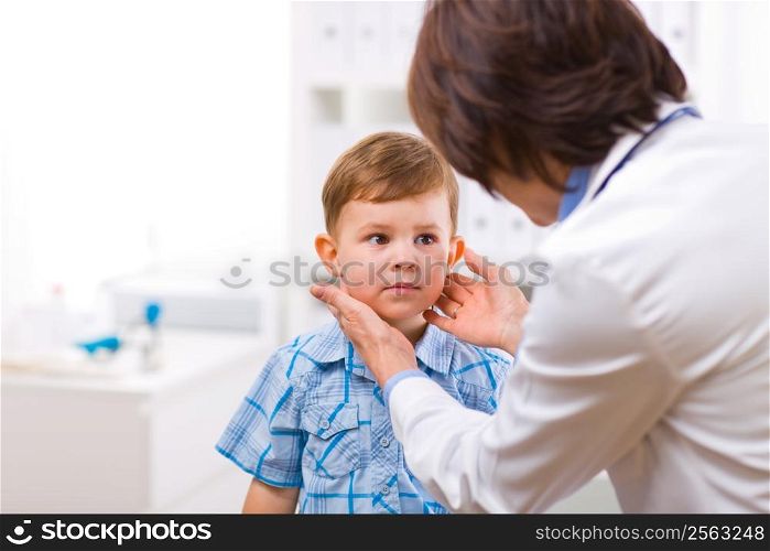 Senior female doctor examining little child boy.