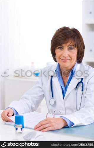 Senior female doctor sitting at desk working at offiice.