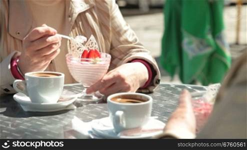 Senior Female Friends Eating Dessert At Outdoor Cafe