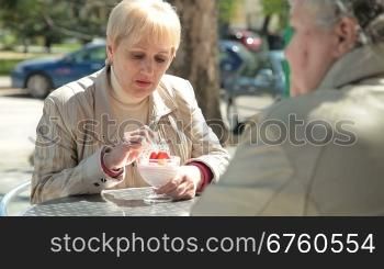 Senior Female Friends Eating Dessert At Sidewalk Cafe