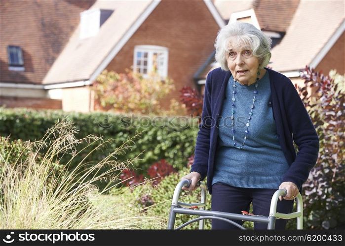 Senior Female In Garden Using Walking Frame